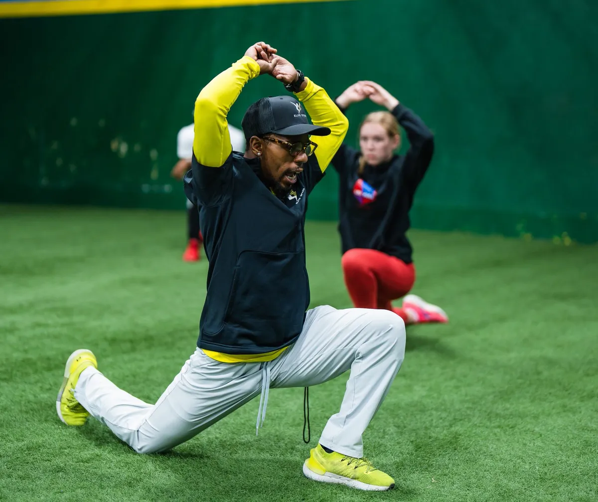 An Elite Speed coach leading a warm-up stretch on the indoor turf in Granite City, Illinois